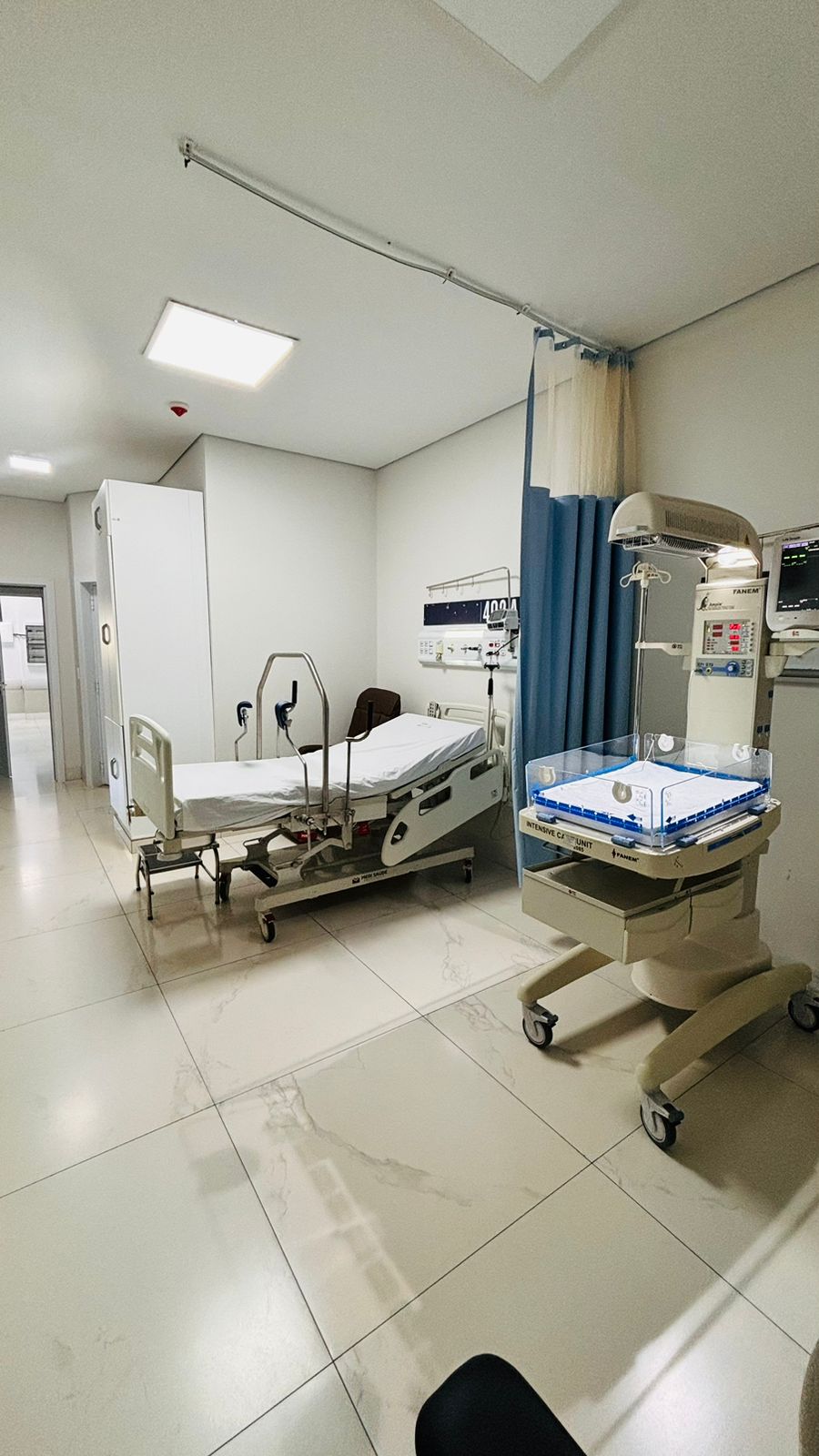 Quarto de maternidade com leito hospitalar e cadeira